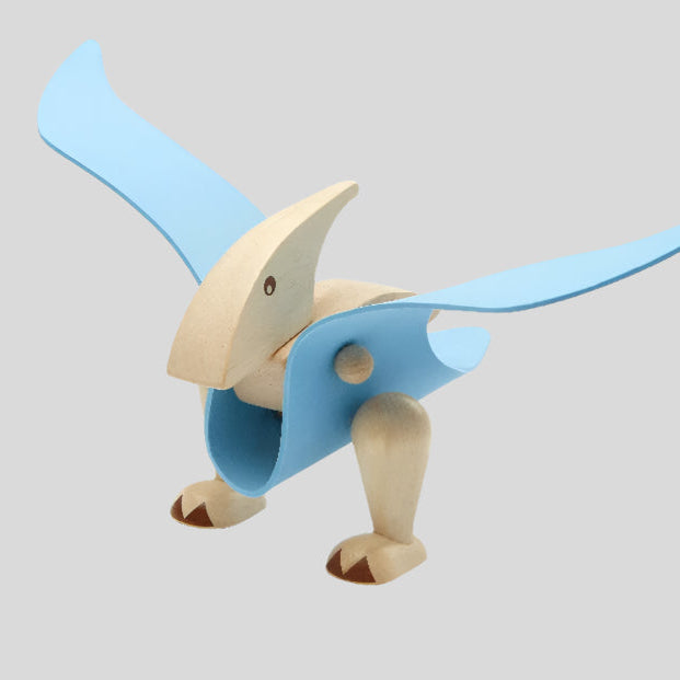 A craft kit dinosaur toy made of rubber and wood with a blue saddle and beige body.