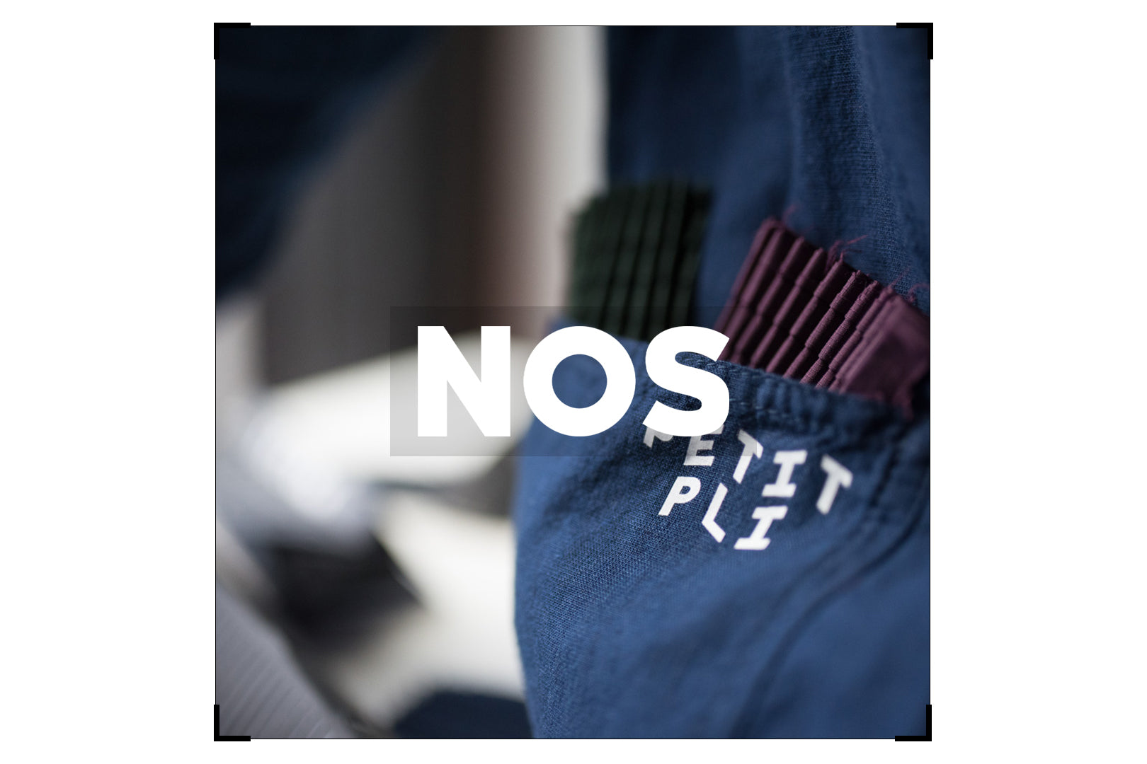 Close-up of Petit Pli’s pleated blue fabric, featuring the brand name and NOS logo, showcasing innovative expandable clothing design.