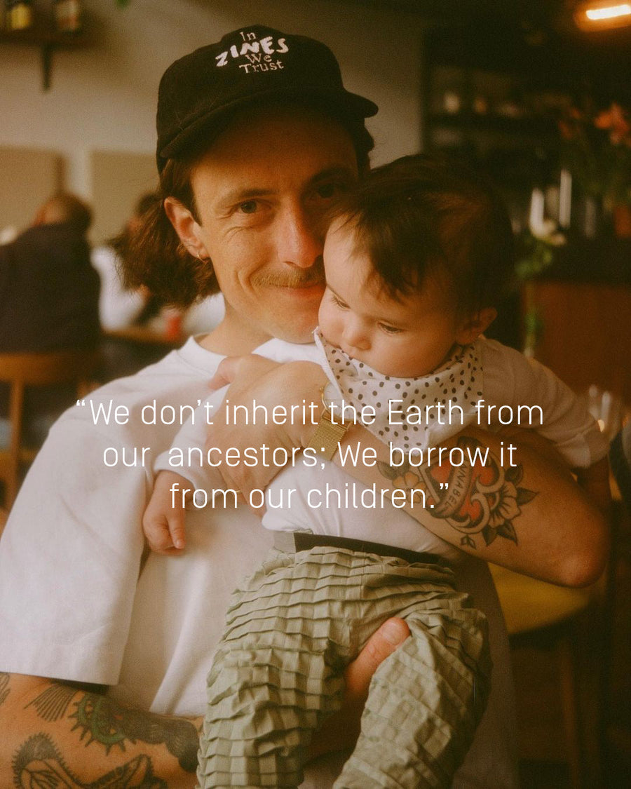 A Father embraces his child in a cozy indoor setting with a quote overlay, “We borrow the Earth from our children,” highlighting love, legacy and sustainability.