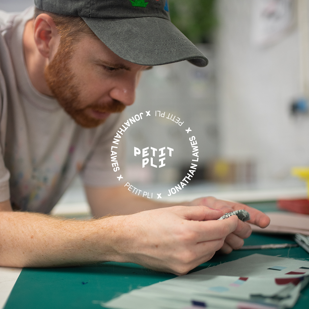 Jonathan Lawes looks intensly at printed shapes on fabric whislt leaning over his bench
