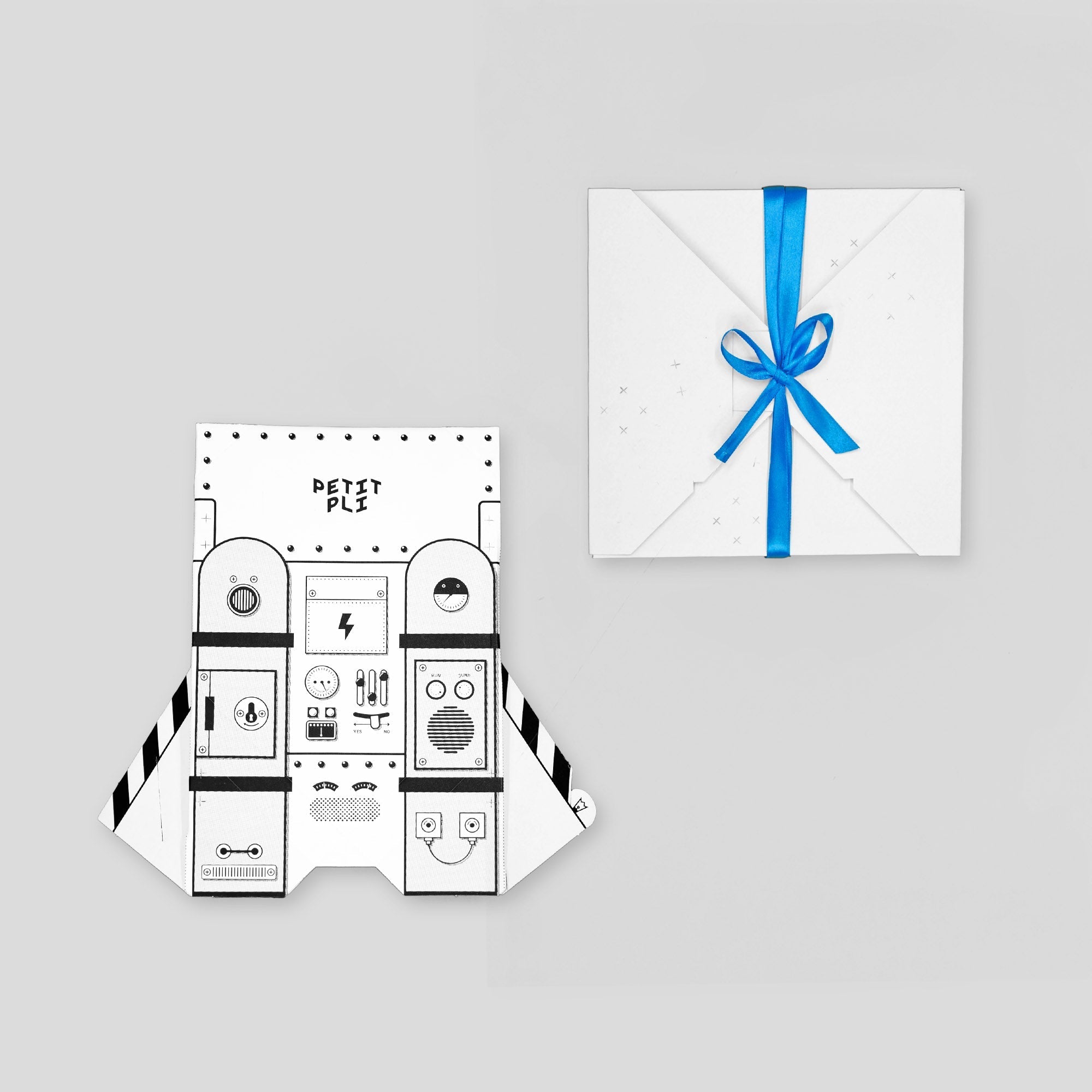 Petit Pli Jetpack Packagaing shown with playful spaceship control panel design, a zero waste gift wrapped in blue ribbon to inspire imaginative LittleHuman adventures.
