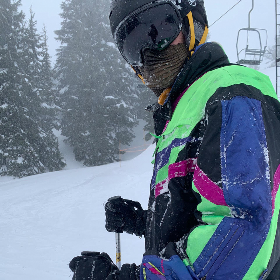 Skier in vibrant winter gear wearing Petit Pli MSK stands on a snowy slope, ski poles in hand - capturing Josh’s pandemic exploration.