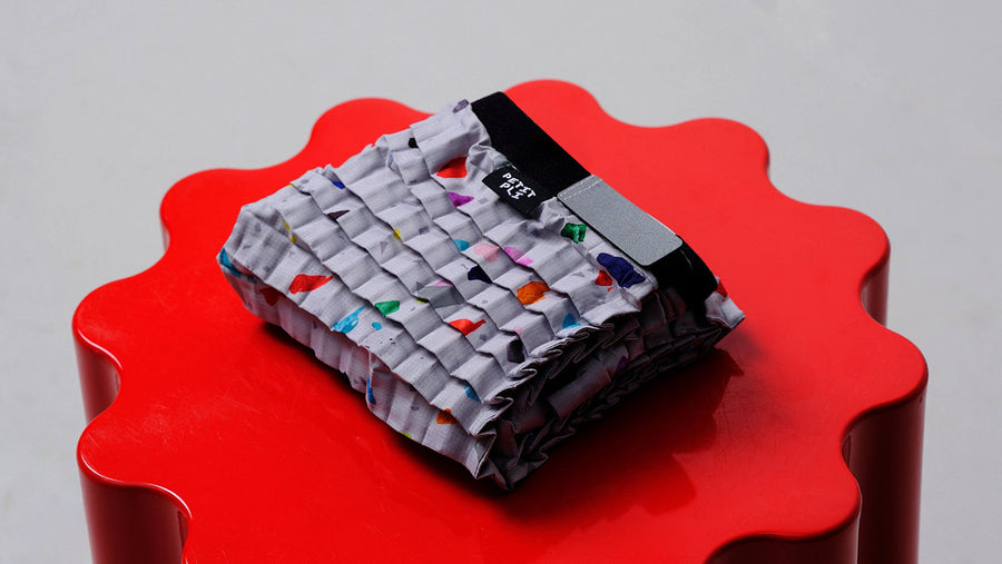 Foldeayed on rd Petit Pli x Time & Space garment with terrazzo-inspired print, displed pedestal ahead of London Fashion Week 2025 launch.