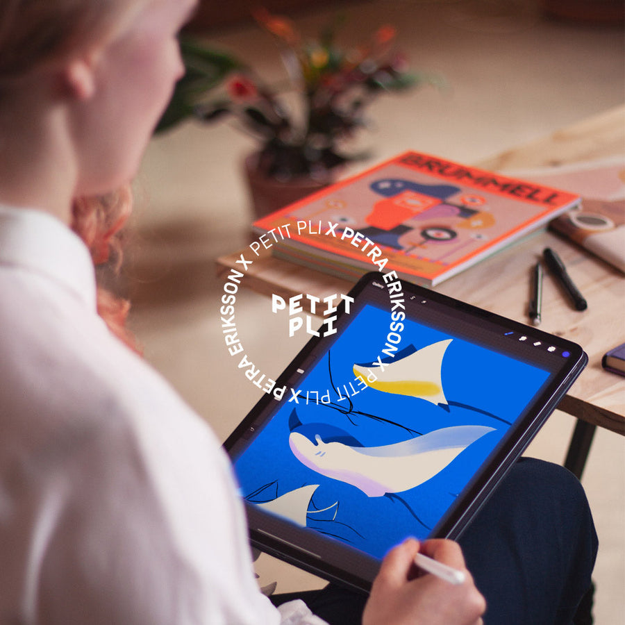 Petra Eriksson works on a tablet at a wooden desk, creating bold abstract shapes for Petit Pli’s Print 12 collaboration.