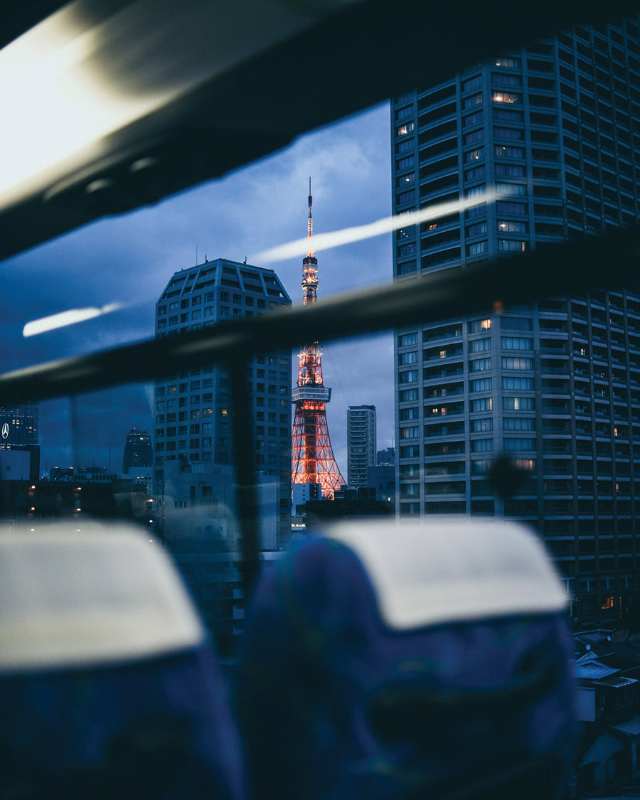 Tokyo Tower glows at dusk, seen through a bus window, symbolising Petit Pli’s first Tokyo pop-up at Isetan Shinjuku and the city’s vibrant fashion scene.