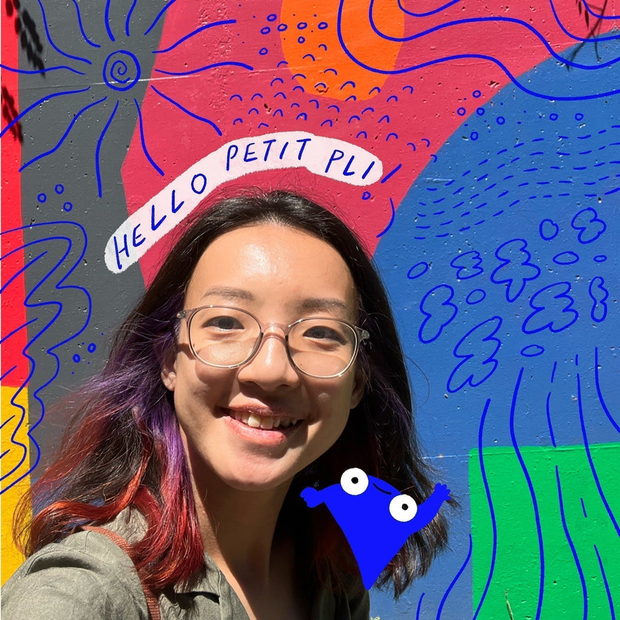 Qiyun of The Weird and Wild smiles in front of a vibrant mural with abstract shapes and a speech bubble saying “HELLO PETIT PLI.”