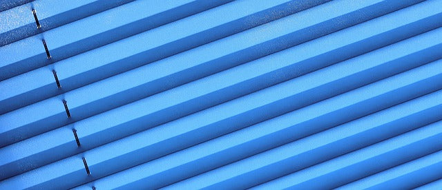 Close-up of vibrant blue blinds, symbolising clarity and simplicity, reflecting Petit Pli’s minimalist approach to kids’ wardrobes and sustainable living.