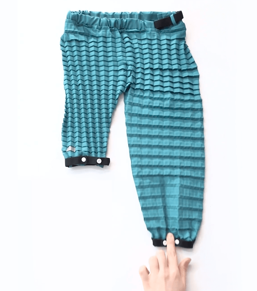 Petit Pli versatile bottoms, one leg stretched to evidence how they to grow with LittleHumans through 7 sizes, offering comfort, style and sustainable innovation.